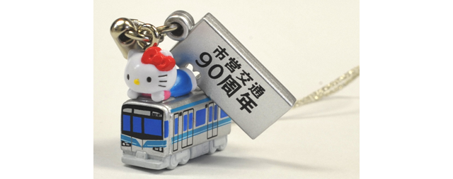 商品写真です。銀色の車体に青色のラインが入った地下鉄車両の上にハローキティがうつ伏せに寝そべって乗っています。